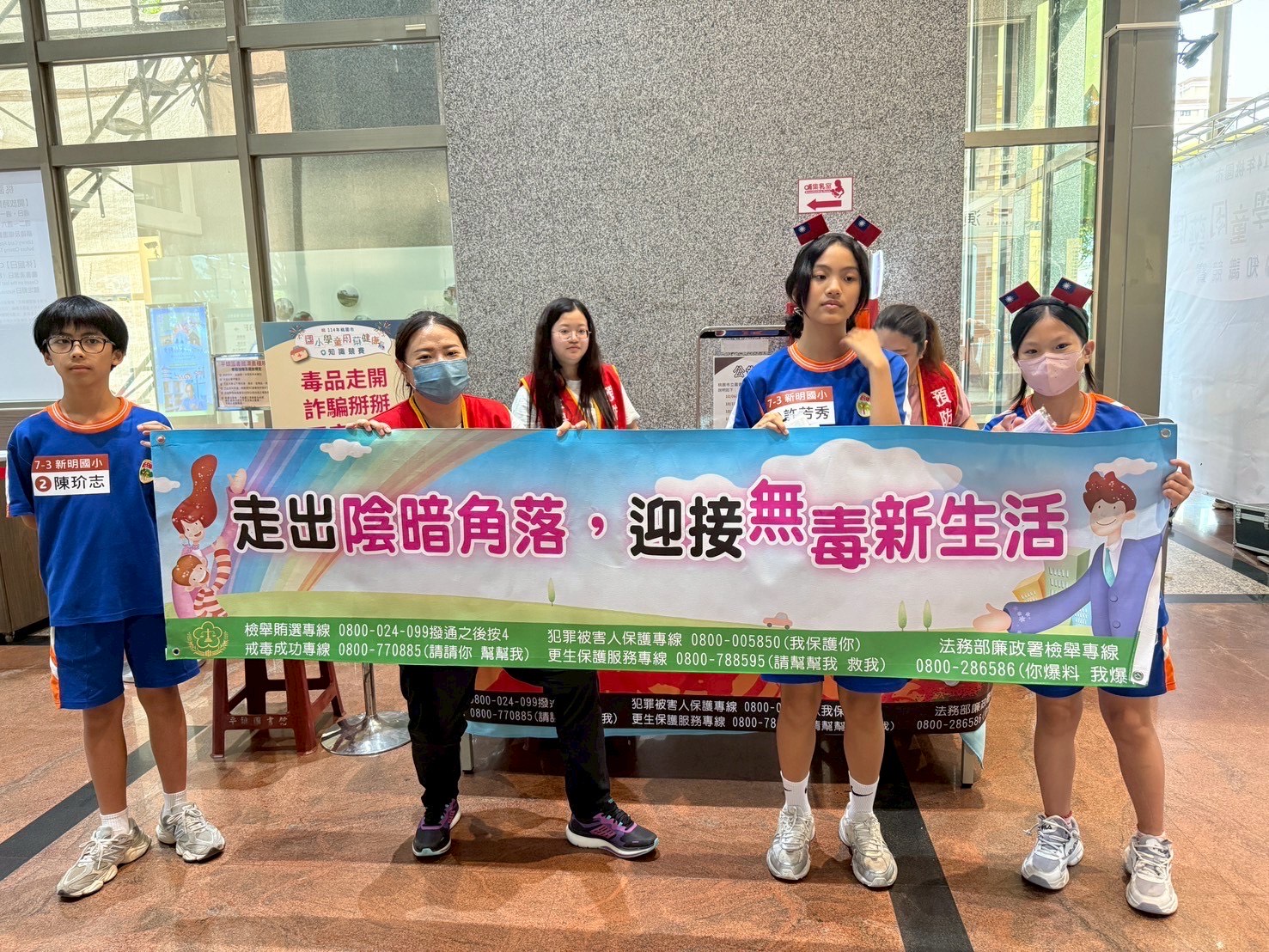 本署同仁和學童一起高舉反毒打詐活動布條